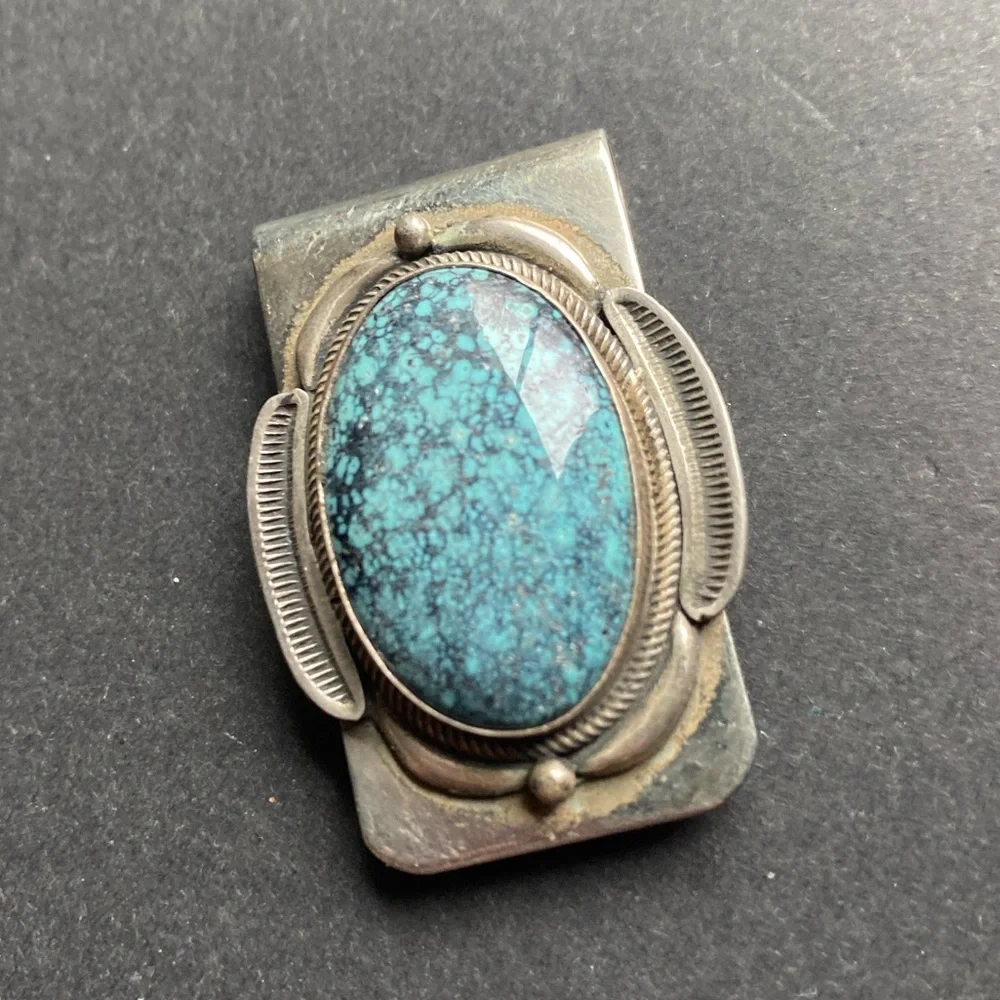 Silver toned money clip with polished blue stone. No stamps.
